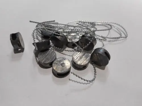 Remeha Zubehör, bestehend aus mehreren Metallteilen mit Durchgangsbohrungen und einer Schnur, zur Befestigung und Sicherung von Beuteln oder ähnlichem Material.